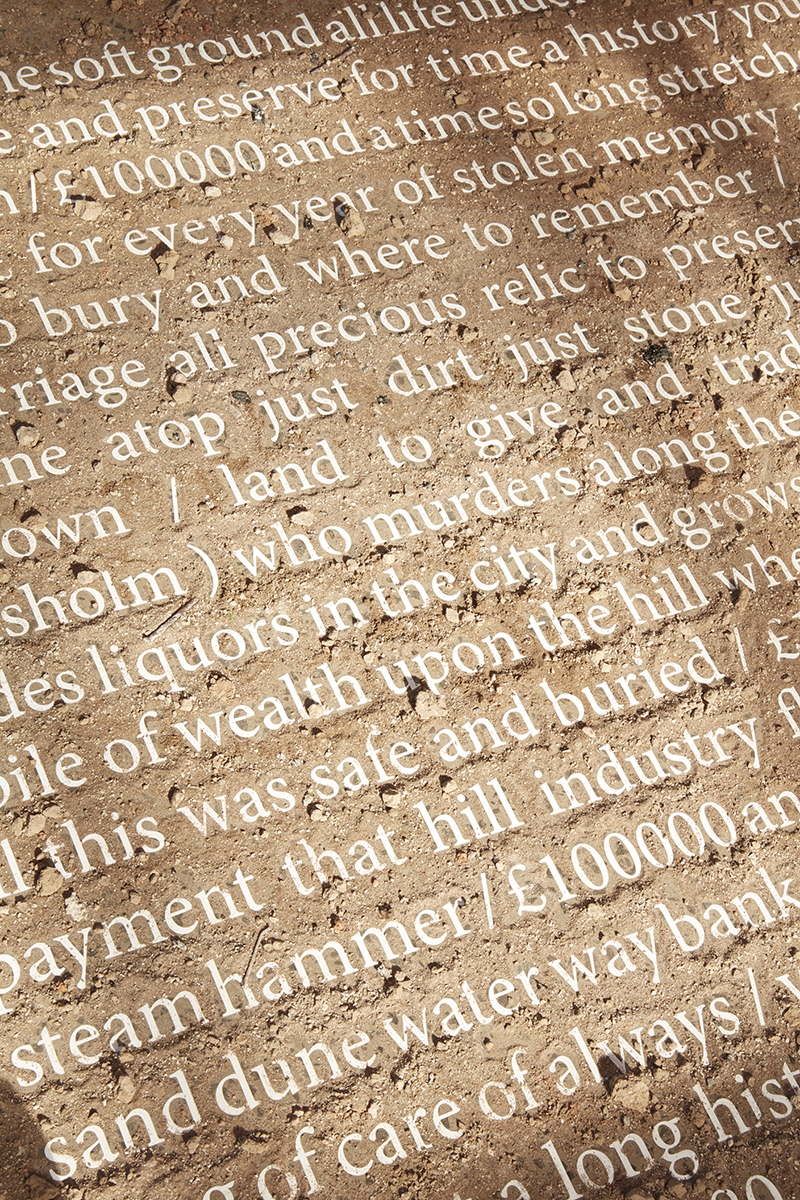 White text of a poem can be read through a thin layer of dirt.