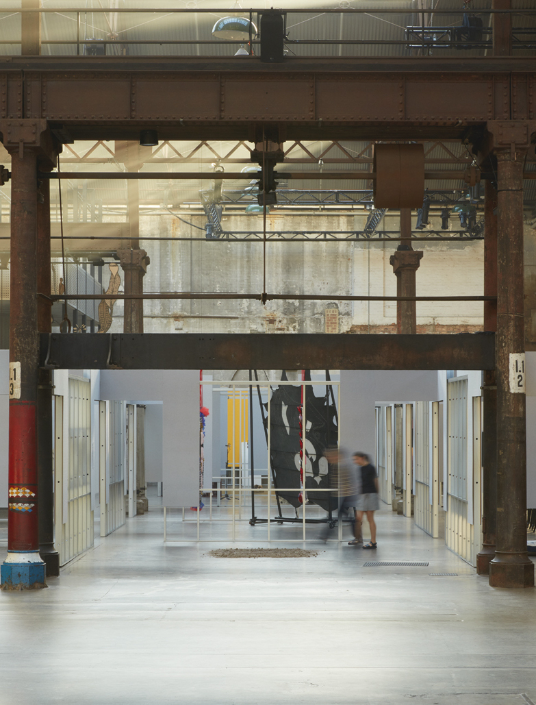 People walk through an exhibition space. The dirt from £100,000 can be seen on the concrete floor.